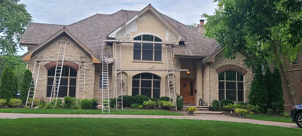 Klasek crew on ladders repairing fascia and trim along the roofline before re-hanging gutters