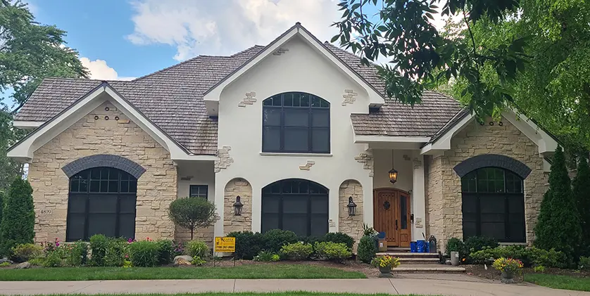 Stone-and-stucco Cook County home with steep rooflines and deep eaves where Klasek installs seamless gutters